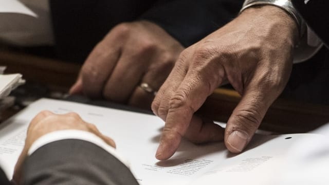Drei Männer zeigen auf Dokumente Drei Männer zeigen auf Dokumente