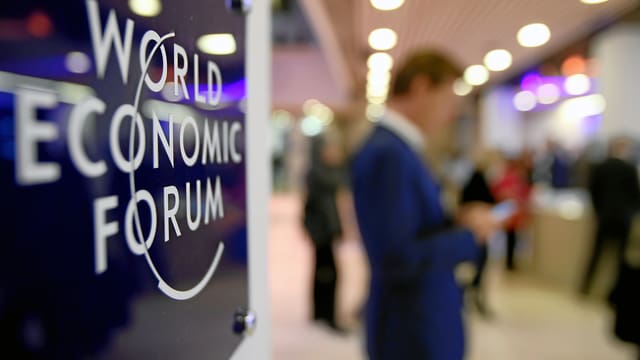 Teilnehmer am WEF 2015 guckt auf sein Handy. Teilnehmer am WEF 2015 guckt auf sein Handy.