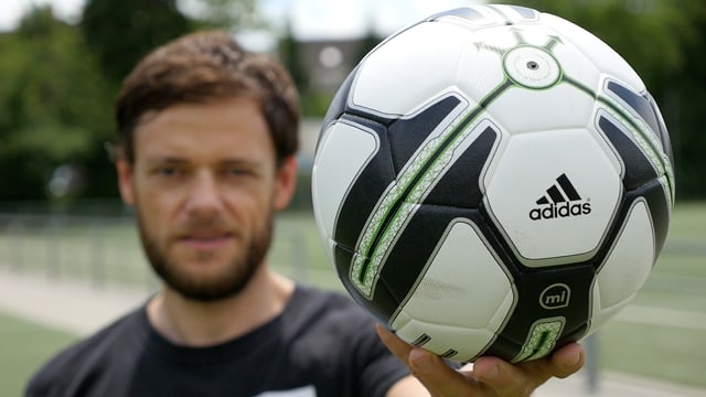 Ein Mann hält einen Fussball in die Kamera. Ein Mann hält einen Fussball in die Kamera.