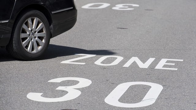Auto fährt über Schriftzug Tempo 30 auf der Strasse Auto fährt über Schriftzug Tempo 30 auf der Strasse