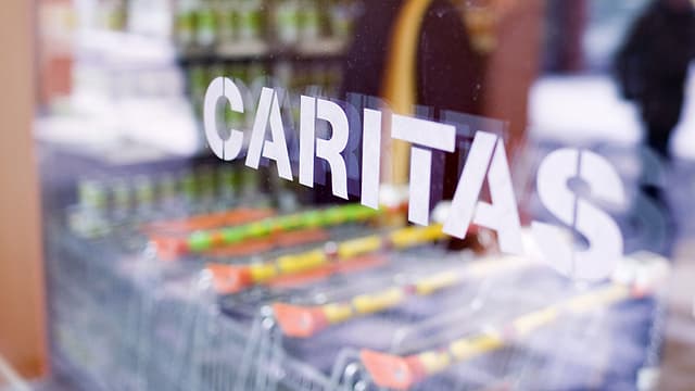 Frontscheibe eines Caritas-Marktes, Caritas-Schriftzug in weiss. Im Innern eine Reihe von Einkaufwagen.