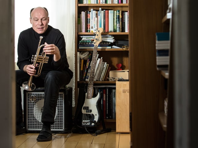 Dieter Ammann sitzt mit Instrumenten zwischen Bücherregalen Dieter Ammann sitzt mit Instrumenten zwischen Bücherregalen