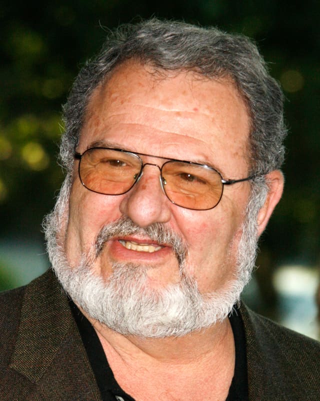 John Milius mit Bart und Brille. John Milius mit Bart und Brille.