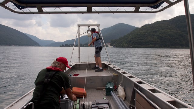 Zwei Männer auf einem Boot. Rechts der Monte San Giorgio. Zwei Männer auf einem Boot. Rechts der Monte San Giorgio.