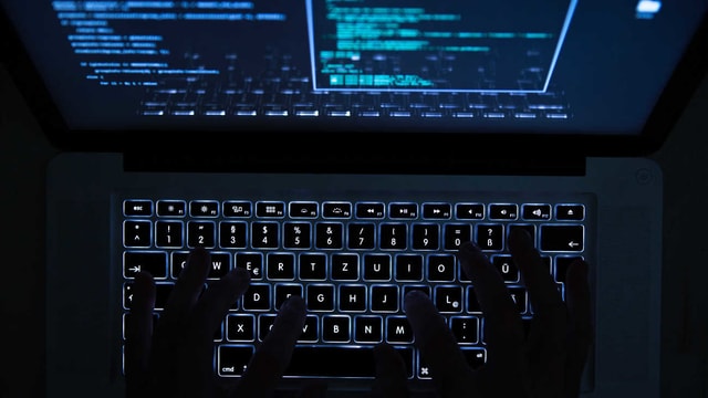 Zwei Hände auf einer beleuchteten Laptop-Tastatur. Zwei Hände auf einer beleuchteten Laptop-Tastatur.