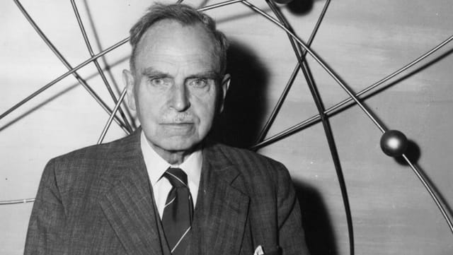 ein schwarz-weiss Foto eines Mannes vor einem Atommodell ein schwarz-weiss Foto eines Mannes vor einem Atommodell