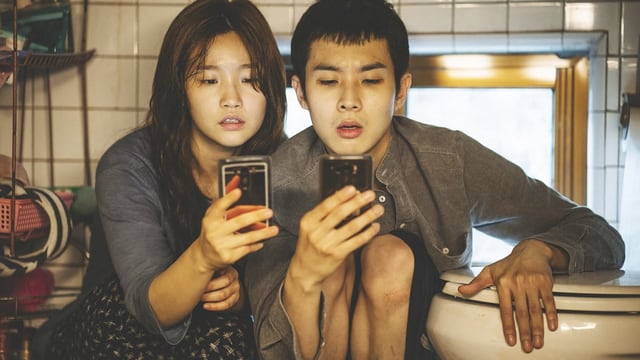 Eine junge Frau und ein junger Mann blicken staunend auf ihre Smartphones. Eine junge Frau und ein junger Mann blicken staunend auf ihre Smartphones.