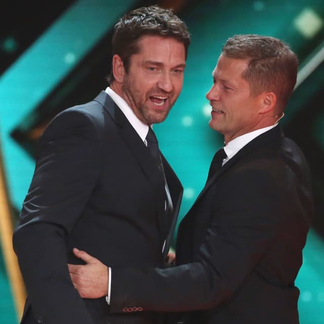 Laudator Til Schweiger umarmt Preisträger Gerard Butler auf der Bühne. Laudator Til Schweiger umarmt Preisträger Gerard Butler auf der Bühne.