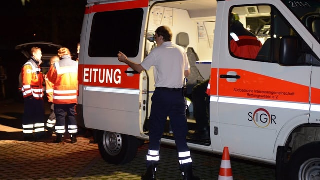 Menschen stehen vor einem Krankenwagen Menschen stehen vor einem Krankenwagen