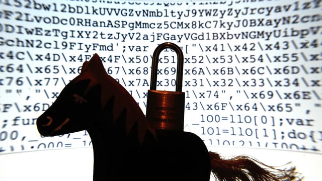 Ein Spielzeugpferd mit einem Vorhängeschloss auf dem Rücken vor einem Bildschirm voller Codes. Ein Spielzeugpferd mit einem Vorhängeschloss auf dem Rücken vor einem Bildschirm voller Codes.