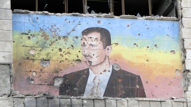 Ein mit Einschusslöchern durchdrungenes Bild von Bashar al-Assad. Ein mit Einschusslöchern durchdrungenes Bild von Bashar al-Assad.