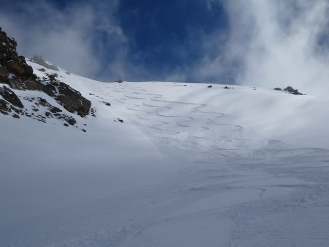 Schneehang mit Spuren von Skifahrern, der Himmel ist stahlblau.