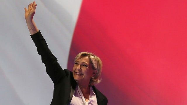 Marine Le Pen nach hinten winkend.