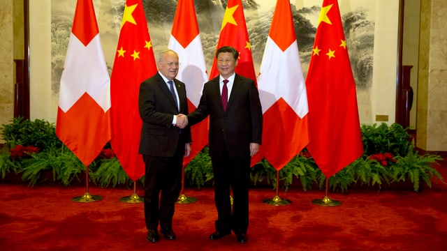 Schneider-Ammann und Xi geben sich die Hand, hinter ihnen mehrere Schweizer- und Chinafahnen. Schneider-Ammann und Xi geben sich die Hand, hinter ihnen mehrere Schweizer- und Chinafahnen.