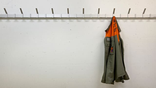 Eine Zivilschutzjacke hängt einsam an einer Wand Eine Zivilschutzjacke hängt einsam an einer Wand