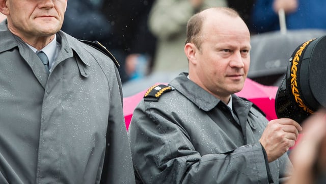 Zwei Männer in dunkelgrauem Uniform-Mantel stehen nebeneinander, einer zückt seinen Hut. Zwei Männer in dunkelgrauem Uniform-Mantel stehen nebeneinander, einer zückt seinen Hut.