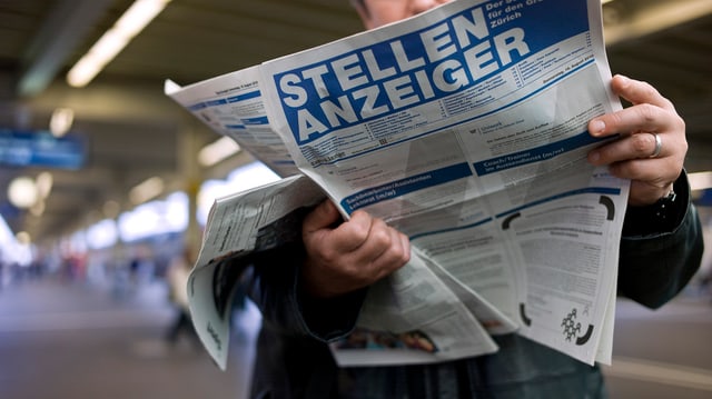 Ein Mann liest den Stellenanzeiger an einem Bahnhof. Ein Mann liest den Stellenanzeiger an einem Bahnhof.