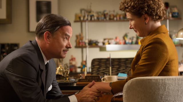 Tom Hanks als Walt Disney sitzt leicht gebeugt vor Emma Thompson als Pamela Travers und hält mit bedeutender Geste ihre Hand. Tom Hanks als Walt Disney sitzt leicht gebeugt vor Emma Thompson als Pamela Travers und hält mit bedeutender Geste ihre Hand.