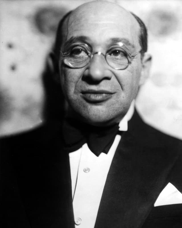 Grünbaum trägt eine Nickelbrille, Anzug mit Fliege. Grünbaum trägt eine Nickelbrille, Anzug mit Fliege.