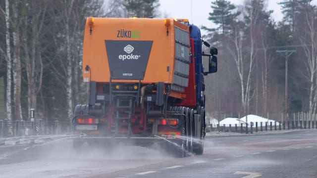 Ein Lastwagen, der gerade Sole auf eine Fahrbahn spritzt. Ein Lastwagen, der gerade Sole auf eine Fahrbahn spritzt.