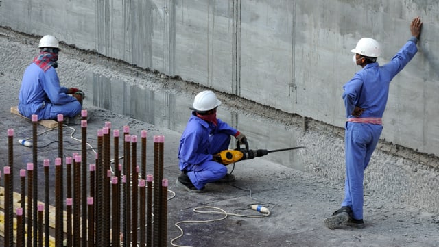 Drei Baurbeiter in einem blauen Overall und gelbem Schutzhelm Drei Baurbeiter in einem blauen Overall und gelbem Schutzhelm
