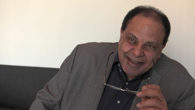 Ein Mann mit Brille in der Hand lächelt. Ein Mann mit Brille in der Hand lächelt.