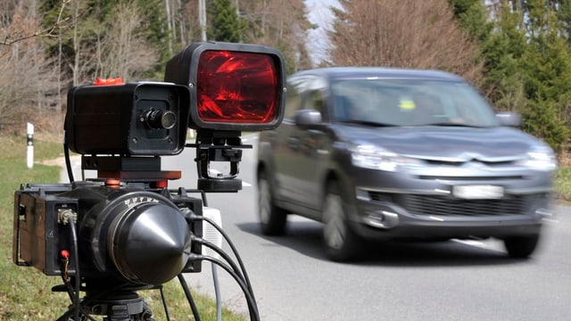 Ein Radargerät steht neben einem fahrenden Auto Ein Radargerät steht neben einem fahrenden Auto