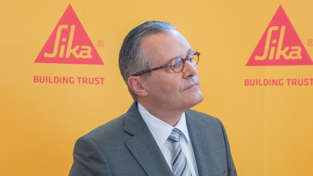 Sika-Präsident Paul Hälg an der diesjährigen GV vor einer gelben Wand mit zwei roten SIka-Logos Sika-Präsident Paul Hälg an der diesjährigen GV vor einer gelben Wand mit zwei roten SIka-Logos