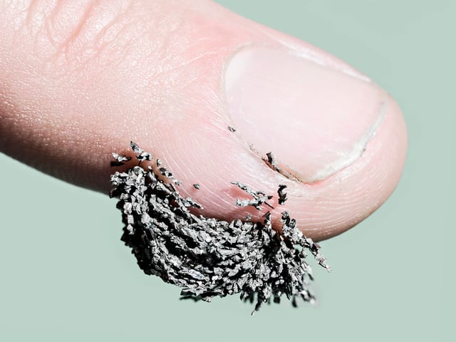 Eine Fingerkuppe, an der kleine Metallsplitter hängen. Eine Fingerkuppe, an der kleine Metallsplitter hängen.