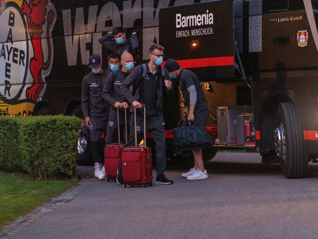 Spieler von Leverkusen verlassen den Teambus mit Maske.