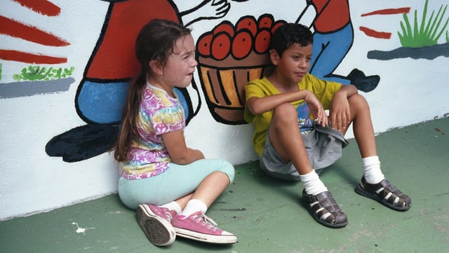 Zwei Kinder sitzen an eine Wand gelehnt am Boden. Zwei Kinder sitzen an eine Wand gelehnt am Boden.