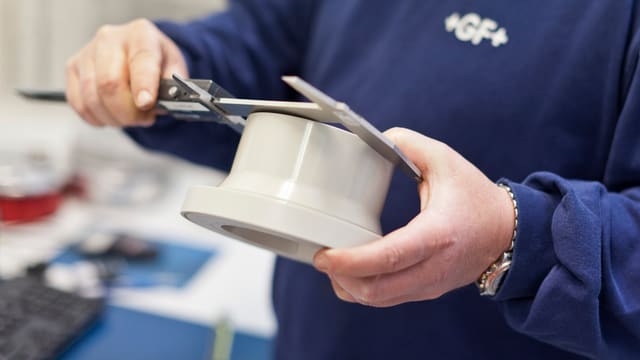 GF-Mitarbeiter misst mit einer Schublehre ein Rohrstück aus GF-Mitarbeiter misst mit einer Schublehre ein Rohrstück aus