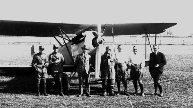 Militärs und Zivilisten vor altem Flugzeug. Militärs und Zivilisten vor altem Flugzeug.