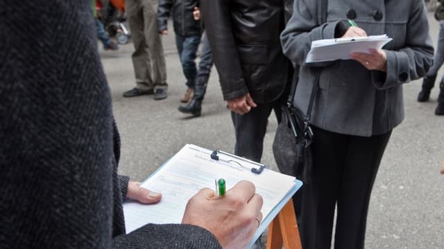 Unterschriftensammlung: Passanten füllen ein Initiativbegehren aus. Unterschriftensammlung: Passanten füllen ein Initiativbegehren aus.