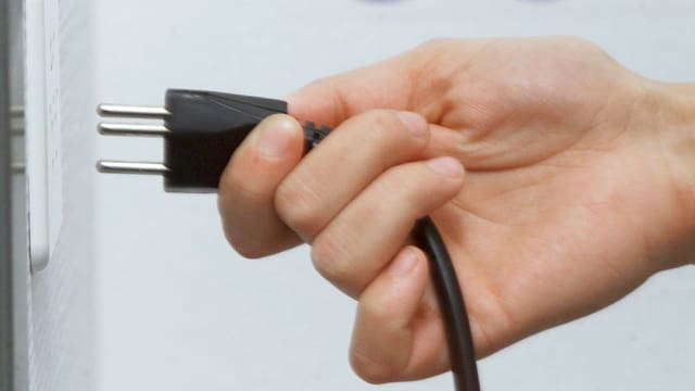 Eine Person zieht einen Stecker Eine Person zieht einen Stecker