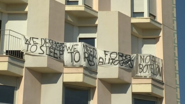 Banner an Balkonen mit Schriften wie "We deserve to sleep".