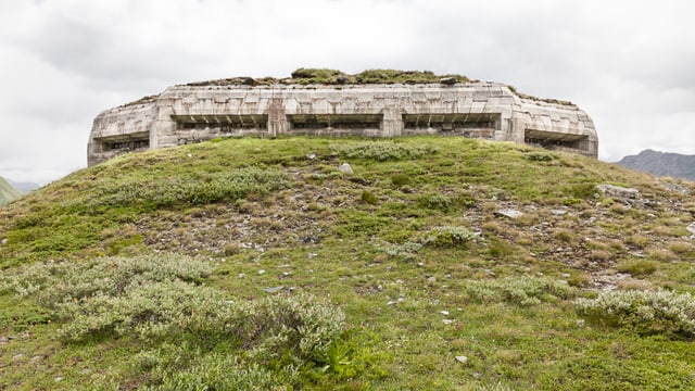 Eine überwachsene Betonfestung auf einem grünen Hügel. Eine überwachsene Betonfestung auf einem grünen Hügel.