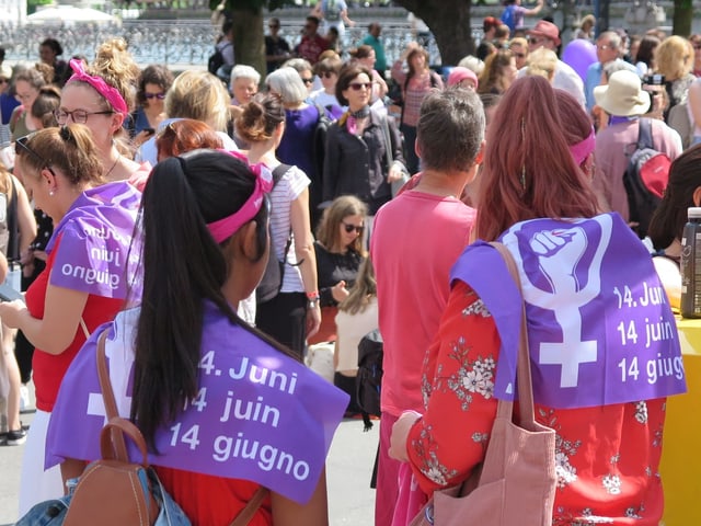 Junge Frauen tragen die Frauenstreikfahne als Umhang.