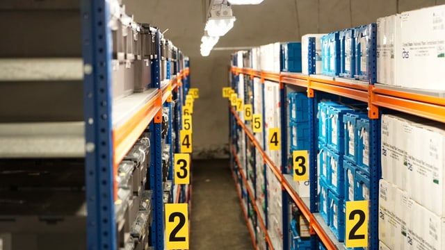 Blick in eine Lagerhalle. Man sieht viele Regale mit Kisten, angeschrieben mit gelben Nummern. Blick in eine Lagerhalle. Man sieht viele Regale mit Kisten, angeschrieben mit gelben Nummern.