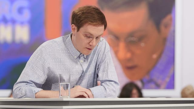 Mannin hellblauem Hemd sitzt an einem tisch und liest von einem Blatt. Mannin hellblauem Hemd sitzt an einem tisch und liest von einem Blatt.