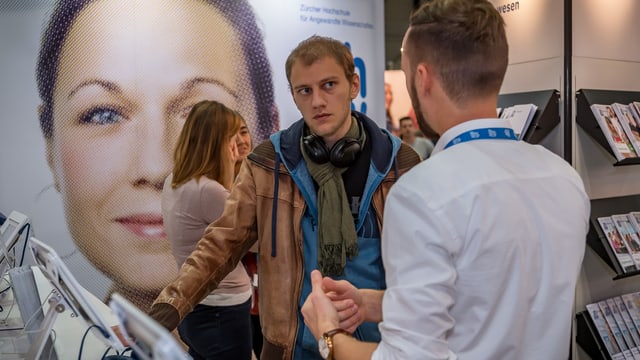 Männer an Messe im Gespräch Männer an Messe im Gespräch