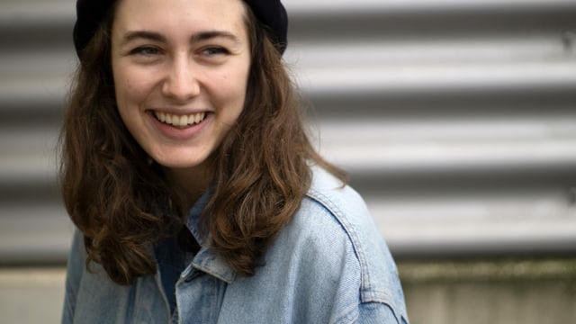 Junge Frau mit braunen Haaren und blauem Hemd lacht Junge Frau mit braunen Haaren und blauem Hemd lacht