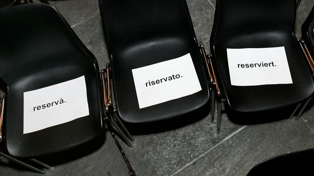 Drei Stühle mit Reserviert-Schildern drauf. Drei Stühle mit Reserviert-Schildern drauf.