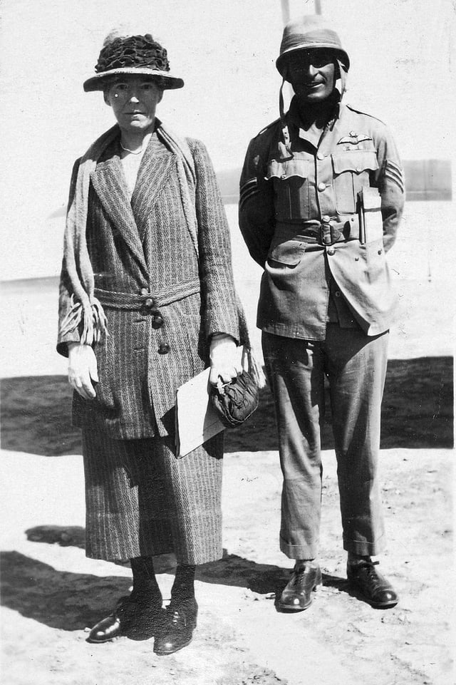 Eine Frau mit Hut steht neben einem Soldaten. Eine Frau mit Hut steht neben einem Soldaten.