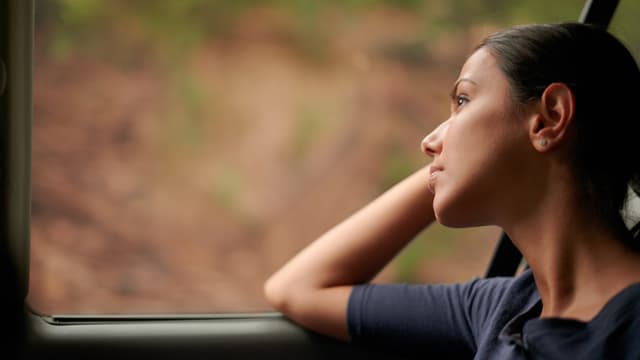 Eine Frau sitzt im Bus und schaut aus dem Fenster. Eine Frau sitzt im Bus und schaut aus dem Fenster.