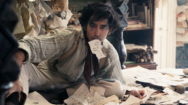 Filmszene: Ein junger Mann sitzt inmitten von beschriebenen Fetzen Papier auf dem Boden. Im Mund hat er ebenfalls einen Fetzen. Filmszene: Ein junger Mann sitzt inmitten von beschriebenen Fetzen Papier auf dem Boden. Im Mund hat er ebenfalls einen Fetzen.