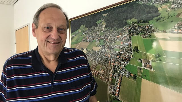 Mann vor einer Lufaufnahme eunes Dorfes. Mann vor einer Lufaufnahme eunes Dorfes.