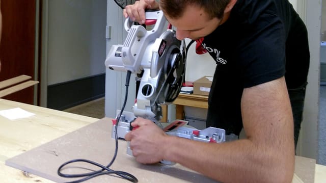 Ein Junge bedient eine Holzschnittmaschine. Ein Junge bedient eine Holzschnittmaschine.