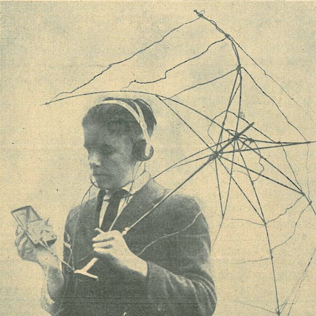 Junge mit ausrangiertem Gerüst eines Regenschirmes, Empfänger in der Hand und Kopfhörer. Junge mit ausrangiertem Gerüst eines Regenschirmes, Empfänger in der Hand und Kopfhörer.