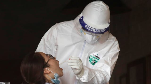 Ein Mann im Schutzanzug testet eine junge Frau auf das Coronavirus. Ein Mann im Schutzanzug testet eine junge Frau auf das Coronavirus.